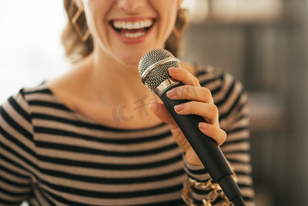 stylish摄影照片_Closeup on young woman singing with microphone in loft apartment
