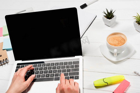 妇女在有办公用品和咖啡的工作场所使用笔记本电脑的剪影