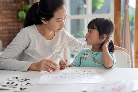 母亲和女儿在家里学习读书写字