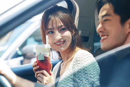 青年伴侣坐在汽车里喝饮料