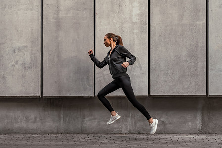 年轻运动员正在体育场附近跑步.侧视图