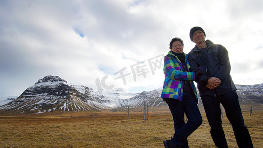 亚洲的年长夫妇享受周年的欧洲之旅。冰岛火山景观山与雪惊人的视图