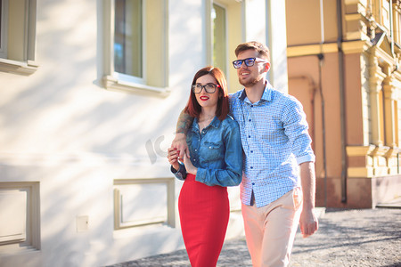 快乐的年轻夫妇站在城里的街上，笑在阳光灿烂的日子