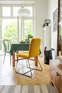 春天摄影照片_芥末椅放置在餐桌上, 配有深绿色桌布和新鲜的柠檬, 真实的照片显示了明亮的房间内饰, 有阳台和木地板