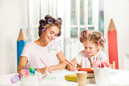 年轻的母亲和她的小女儿用铅笔在家里绘图