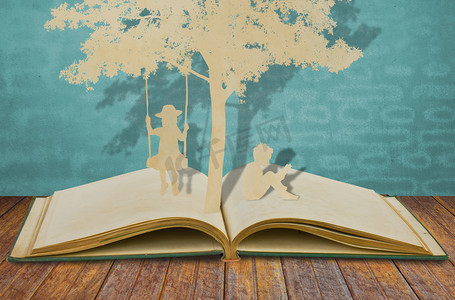 leitura摄影照片_剪纸的儿童阅读一本书和儿童秋千下 tr 上