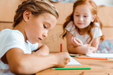 欧美艺术摄影照片_近红头发儿童在纸上画的可爱儿童的选择性焦点 