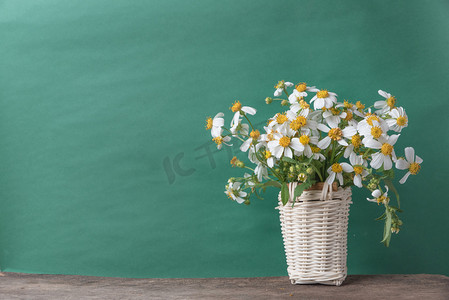 白色的花，在与旧的绿色背景，复古色调的木桌上的篮子里.