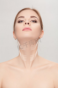 neck摄影照片_woman with arrows on face over grey background. neck lifting con