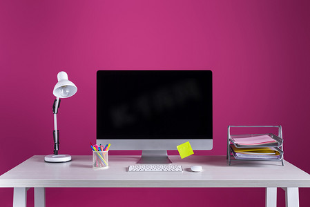 桌上有空白屏幕、办公用品和台灯的台式电脑, 粉红色