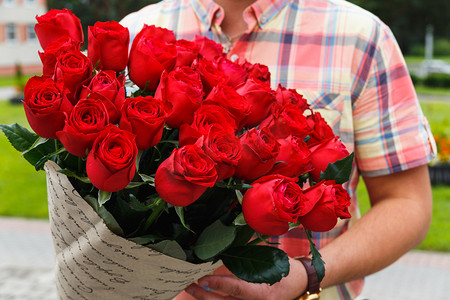 五一大特惠摄影照片_文艺一名男子手持一大束红玫瑰