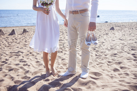 只是已婚夫妇在沙滩上运行脚查看，新郎持有鞋