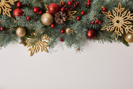 新年金色背景摄影照片_杉木树枝与圣诞节玩具和金色的雪花查出的白色的顶部视图