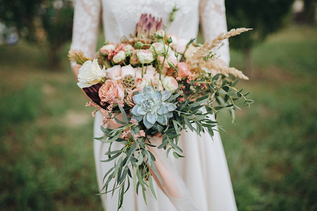 婚纱摄影照片_新娘穿着婚纱站在一个绿色的花园，手里拿着一束鲜花和绿叶