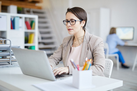 成功的女商人在现代白色办公室工作时使用笔记本电脑的肖像, 复制空间
