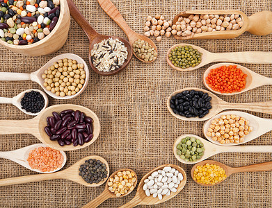 国庆边框红色摄影照片_各种食品配料： 豆类、 豆类、 豌豆、 小扁豆中木勺麻布背景上