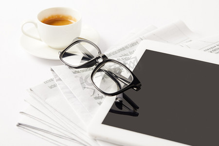 eyeglasses, coffee cup, digital tablet and pile of newspapers, on white