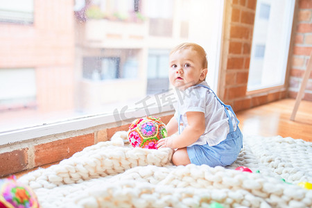 幼稚园时，漂亮的幼儿坐在毛毯上透过窗户眺望