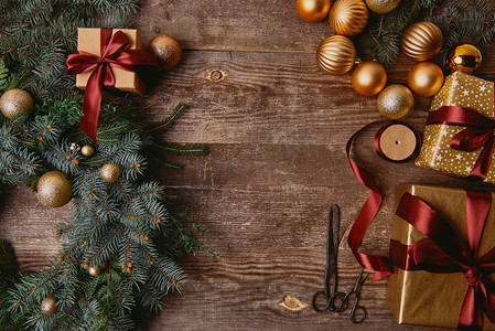 丝带盒摄影照片_在木桌上的圣诞礼物盒, 杉木花圈, 丝带线轴和剪刀的高视图