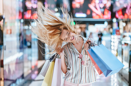 商场购物袋摄影照片_有魅力的年轻快乐的女人正在购物包购物袋在现代购物中心.