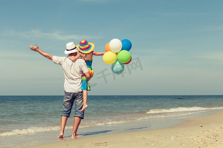 拥抱孩子摄影照片_父亲和女儿用 da 在沙滩上玩耍的气球