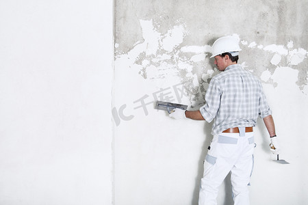 建筑工地内墙上的大肠贴斑工头戴安全帽和防护手套，隔离并复制白墙上的空间