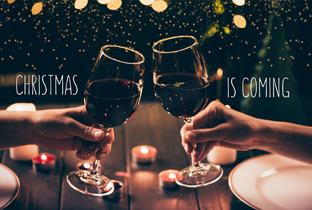 红葡萄酒摄影照片_妇女在送达表碰杯圣诞节