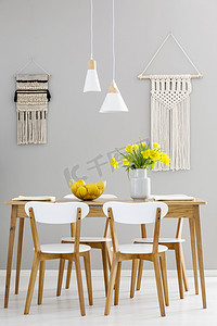 餐饮灯笼摄影照片_白色椅子在木桌与黄色花在灰色饭厅内部与灯。真实照片