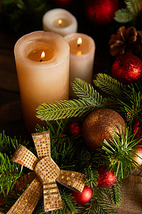 用云杉枝、蝴蝶结和圣诞球在木制桌子上点燃蜡烛