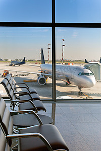在机场和飞机窗口后面的期望的大厅里空扶手椅