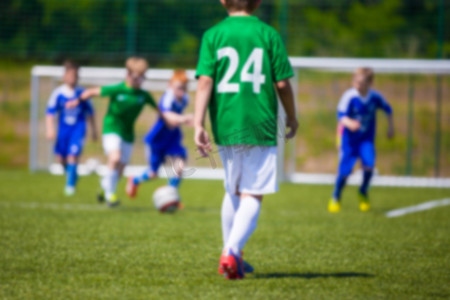 游戏比赛对决摄影照片_模糊的运动足球足球背景。足球比赛的年轻男孩。蓝绿队反对.