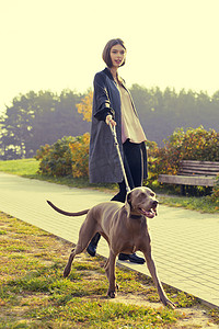 复古欧美背景摄影照片_时尚女孩模型走与她的狗户外公园自然背景