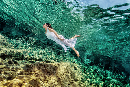 潜水动图摄影照片_在岩石上游动的女人