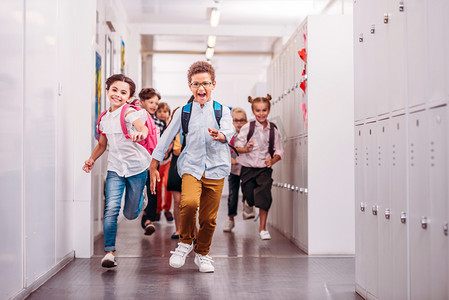 一群可爱的小学生穿过学校走廊在镜头前奔跑