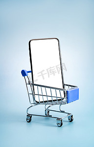 蓝色双十一促销摄影照片_购物车和空白屏幕的手机
