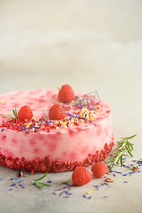 草莓蛋糕摄影照片_美味的覆盆子蛋糕与新鲜的浆果, 迷迭香和干花在灰色的混凝土背景。复制文本的空间。素食, 素食主义者的食物概念.
