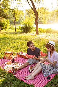 青年伴侣吃西瓜摄影照片_在公园里郊游的幸福情侣