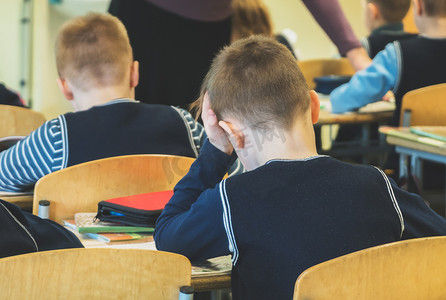 在考试的学生摄影照片_在学校上课累了的小学生。后退视图.