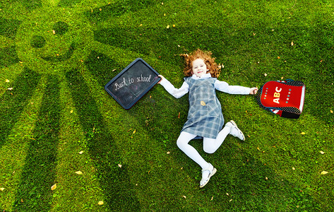 不道德摄影照片_红发女孩躺在公园，高顶视图的绿色草地上.