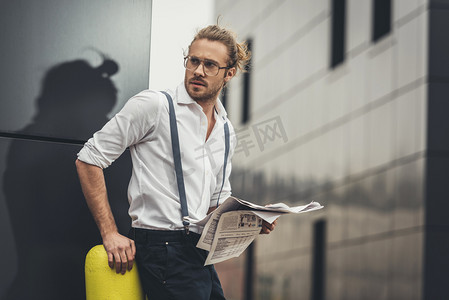 男士长发摄影照片_时尚的男人在路边拿着报纸的男士
