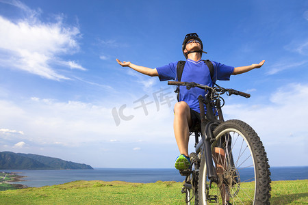 年轻男子坐在一辆山地自行车和张开的双臂放松
