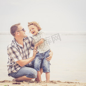 夏天摄影照片_父亲和儿子在沙滩上打了一天时间.