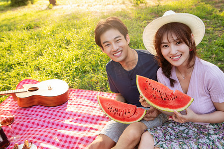 坐在草地上吃西瓜的幸福情侣