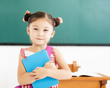 pretty摄影照片_happy little girl holding book in classroom