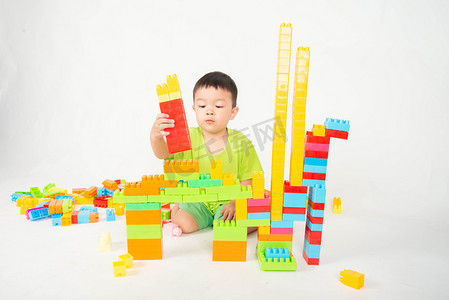 幼儿园家摄影照片_小男孩蹒跚学步玩塑料砖块五颜六色与快乐