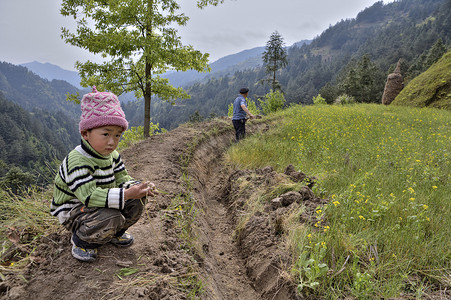 村民摄影照片_农民工程土壤在山区，旁边的男孩