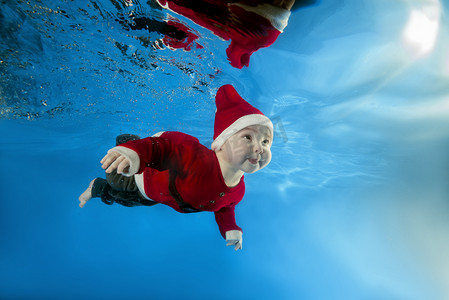 一个小男孩在圣诞老人的成本游泳水在水池