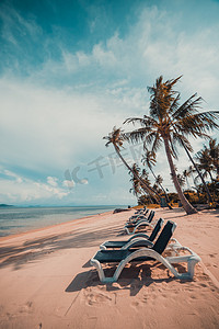 热带海摄影照片_美丽的热带海滩和海与椰子棕榈树和椅子在天堂海岛
