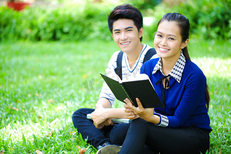 年轻的亚洲学生与书和室外的微笑