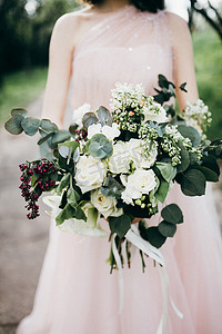 衣服鲜花摄影照片_年轻美丽的新娘摆着鲜花在户外
